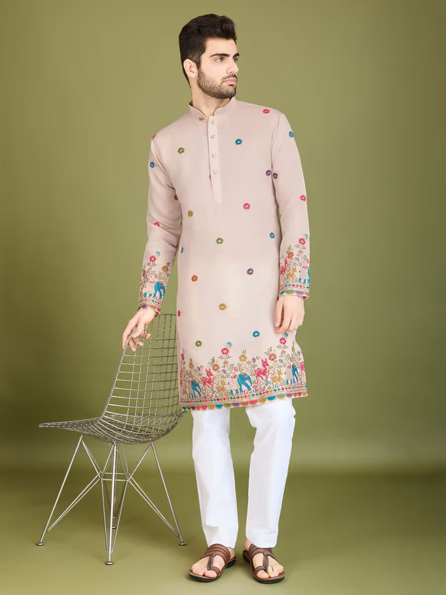 Man wearing a beige kurta with colorful patterns on a green background