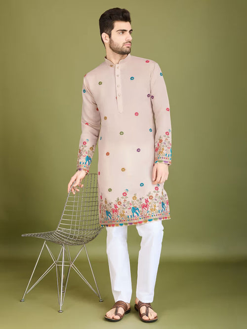 Man wearing a beige kurta with colorful patterns on a green background