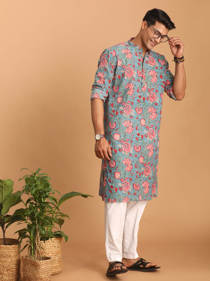 Man wearing a floral kurta with white pants on a beige background