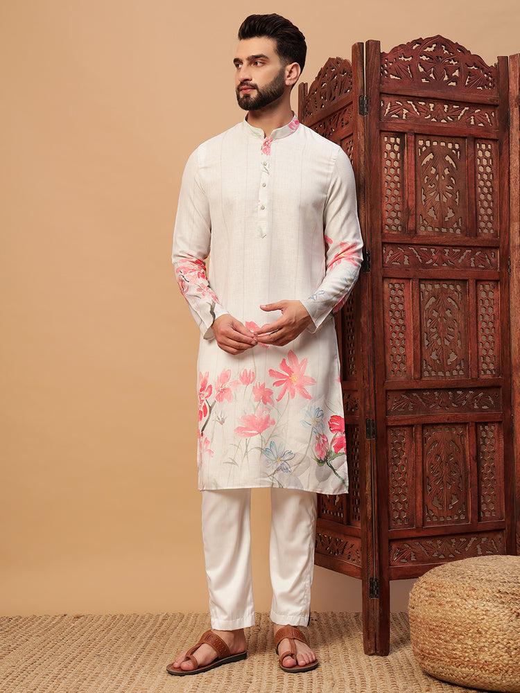 Man wearing a white kurta with floral patterns against a beige wall with a wooden carved screen.