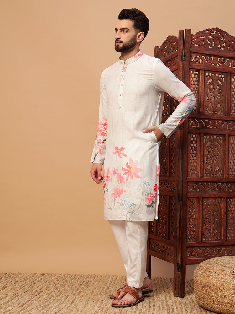 Man wearing a white kurta with floral patterns in a room with a wooden screen and beige wall.