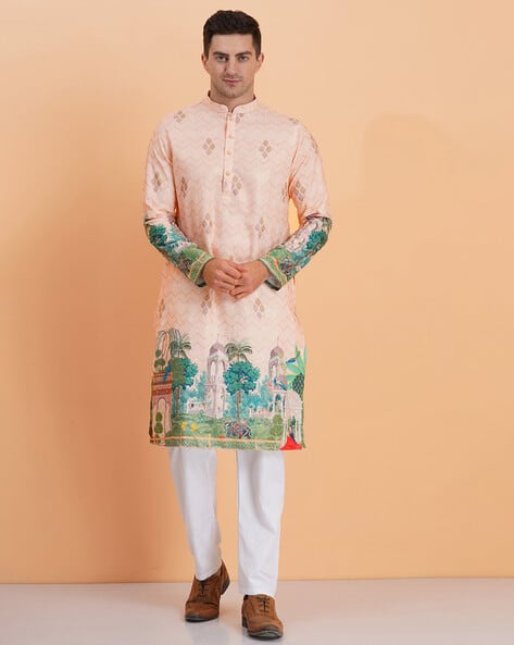 Man wearing a traditional kurta with intricate designs on a peach background