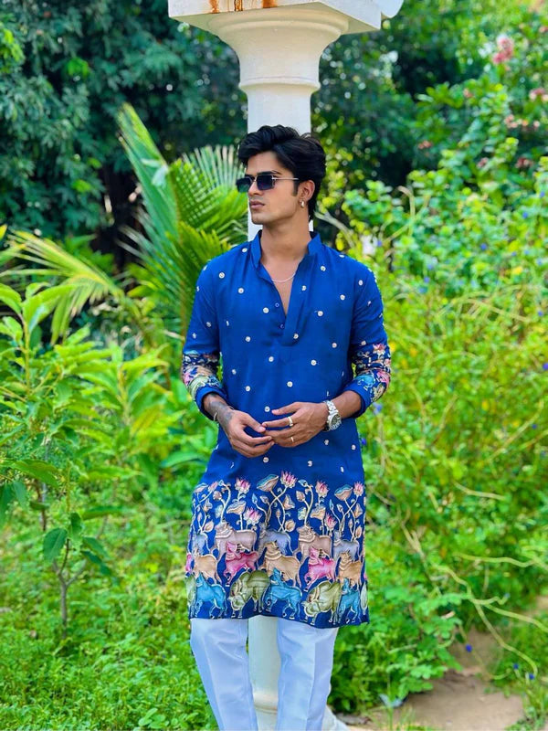 Man wearing a blue kurta with white polka dots and colorful patterns in a garden setting