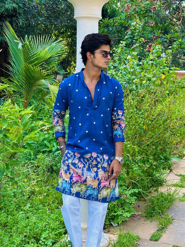 Man wearing a blue kurta with floral design in a garden setting