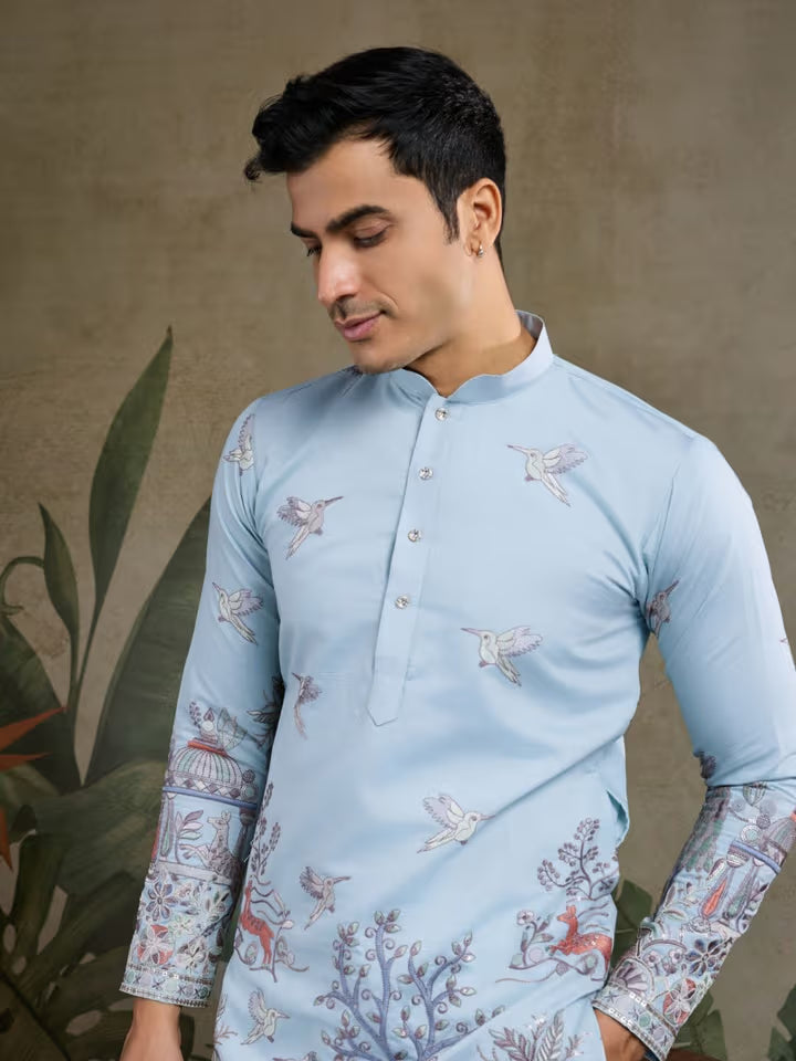 Man wearing a light blue embroidered kurta against a neutral background