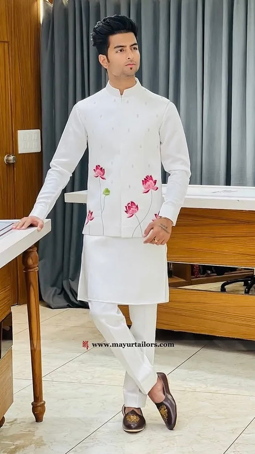 Man wearing a white embroidered kurta with pink flowers in a room.